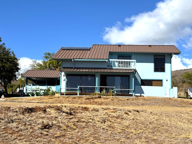 rear view of property featuring a sunroom and a balcony