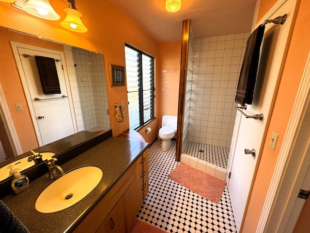 bathroom with tiled shower, vanity, and toilet