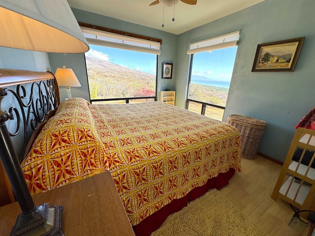 bedroom featuring ceiling fan, light hardwood / wood-style flooring, and a mountain view