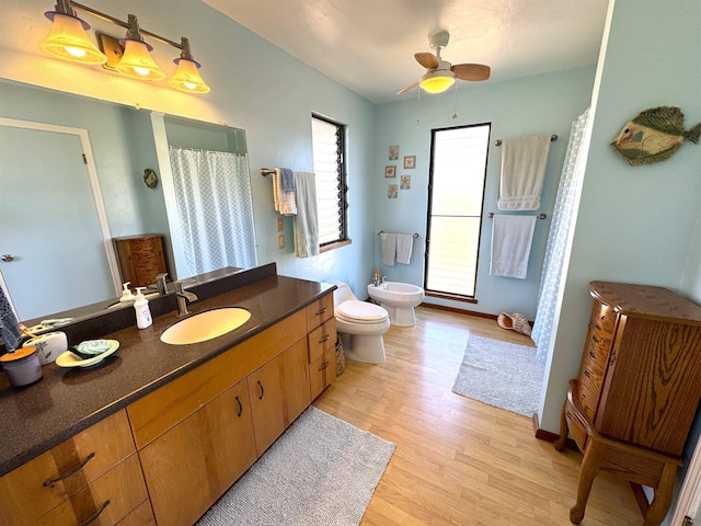 bathroom featuring vanity, a bidet, ceiling fan, toilet, and wood-type flooring