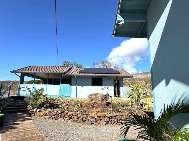 rear view of property featuring solar panels