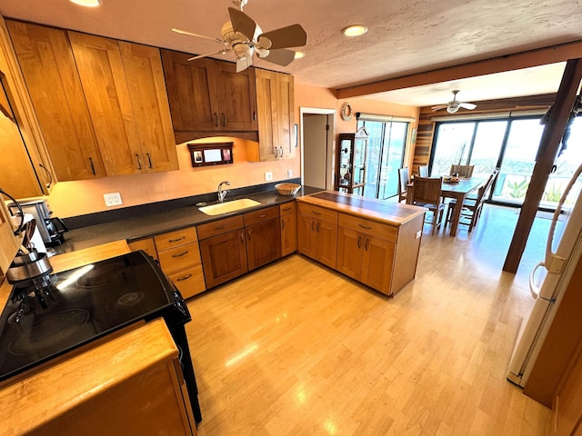 kitchen featuring kitchen peninsula, a textured ceiling, ceiling fan, sink, and electric range