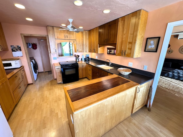 kitchen with black range with electric stovetop, washer / clothes dryer, sink, and light wood-type flooring