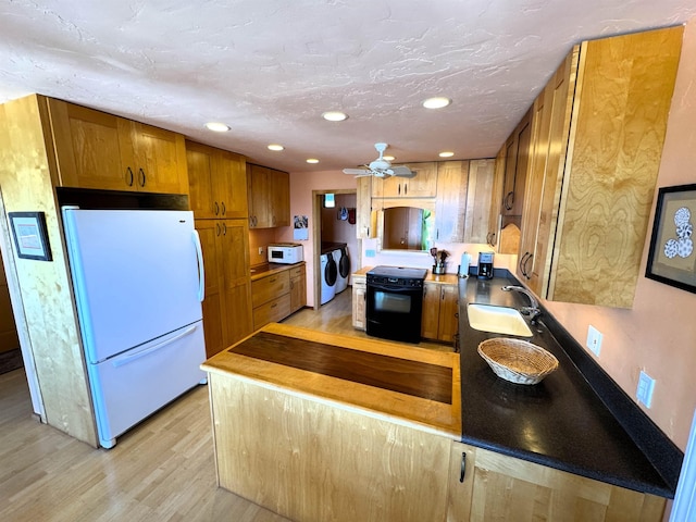 kitchen with white appliances, sink, light hardwood / wood-style flooring, ceiling fan, and separate washer and dryer