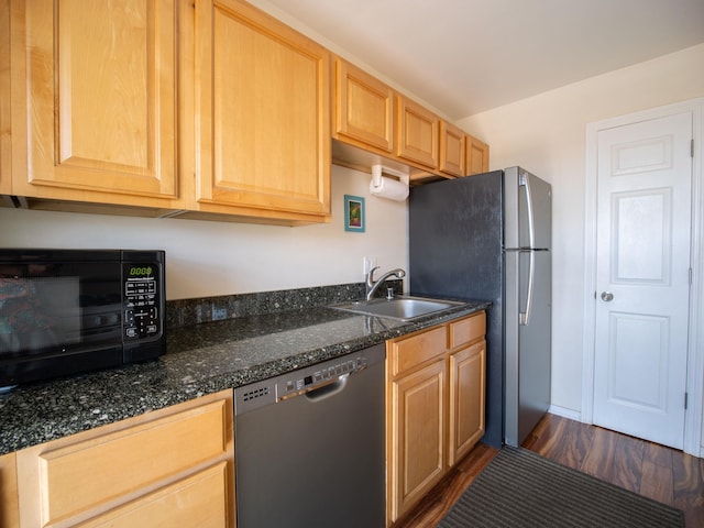 kitchen featuring dark hardwood / wood-style floors, sink, stainless steel appliances, and dark stone counters