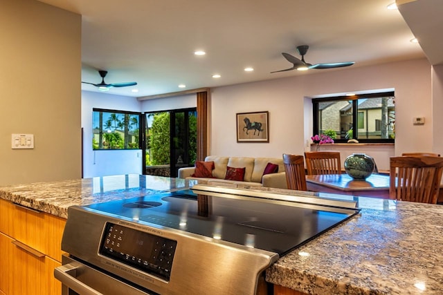 kitchen featuring electric range, ceiling fan, and light stone counters