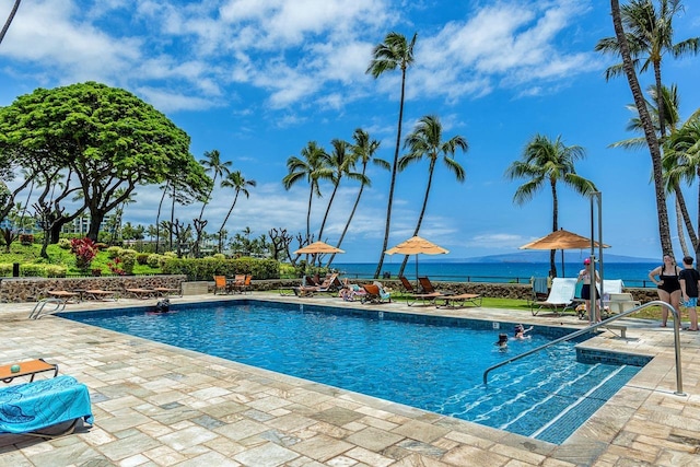 view of pool with a water view and a patio