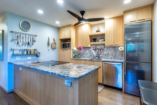 kitchen featuring appliances with stainless steel finishes, sink, kitchen peninsula, light stone counters, and light hardwood / wood-style flooring