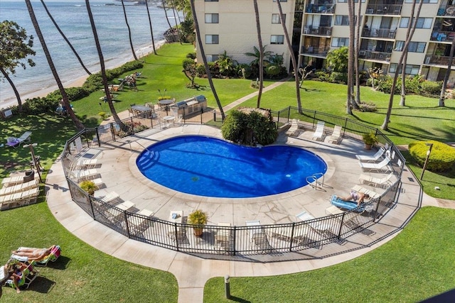 view of swimming pool with a water view, a lawn, and a patio area