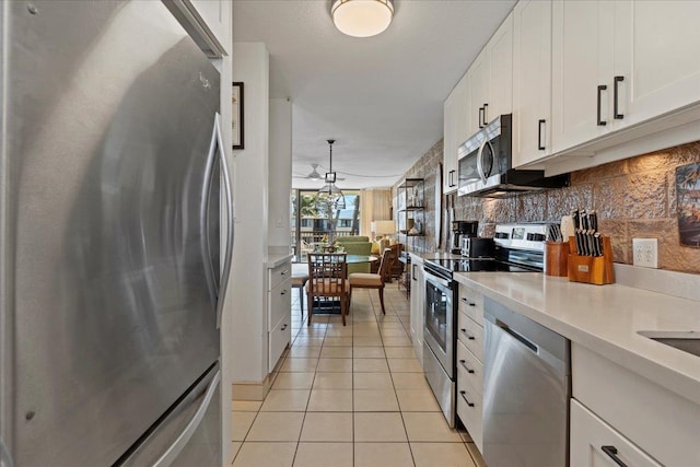 kitchen with white cabinetry, hanging light fixtures, backsplash, light tile flooring, and stainless steel appliances