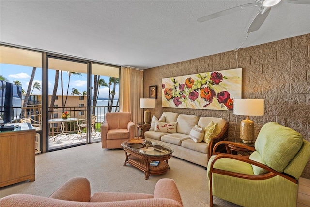 living room with light carpet, a wall of windows, ceiling fan, and a textured ceiling