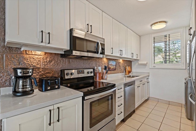 kitchen with stainless steel appliances, light tile flooring, tasteful backsplash, white cabinetry, and sink