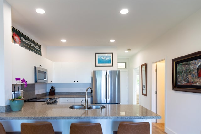 kitchen featuring a breakfast bar, a peninsula, appliances with stainless steel finishes, and a sink