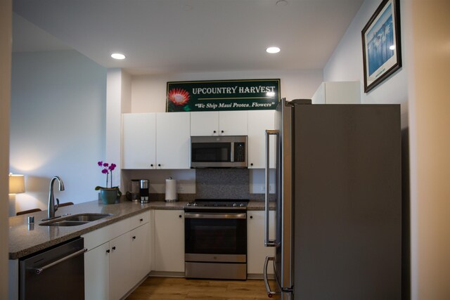 kitchen featuring white cabinets, light wood-style floors, appliances with stainless steel finishes, and a sink