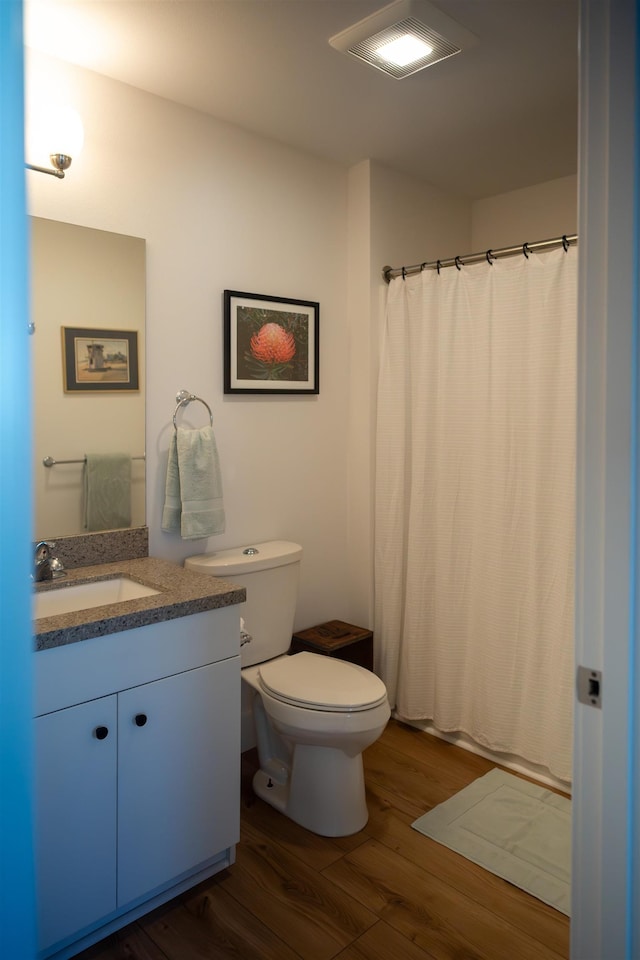 full bath featuring curtained shower, toilet, wood finished floors, and vanity