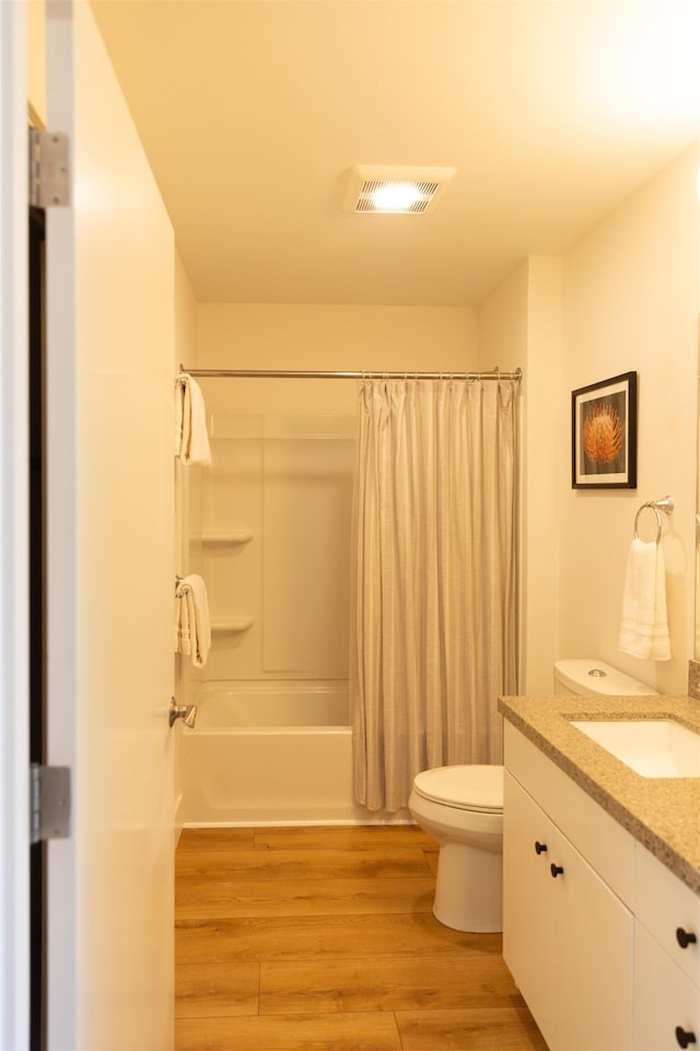 bathroom featuring vanity, wood finished floors, visible vents, toilet, and shower / tub combo with curtain