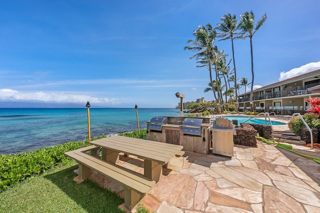 view of patio with area for grilling, a grill, a community pool, and a water view