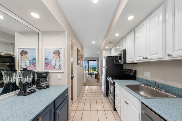 kitchen with white cabinets, appliances with stainless steel finishes, light tile patterned flooring, and sink