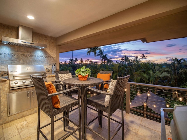 patio terrace at dusk with grilling area, an outdoor kitchen, and a balcony