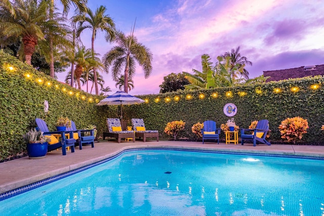 pool at dusk with a patio area