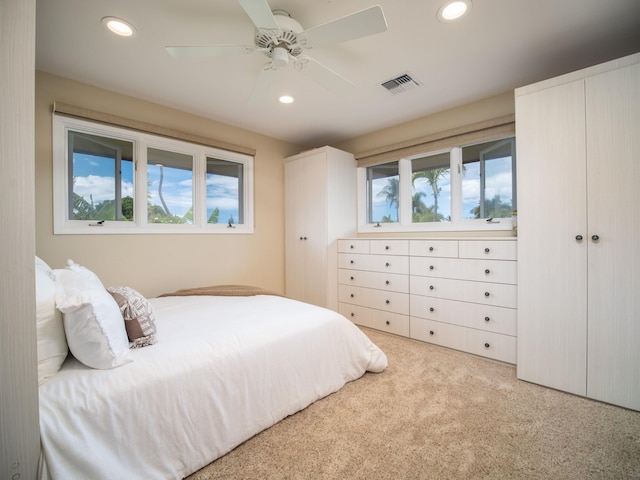 bedroom with ceiling fan, multiple windows, and light colored carpet