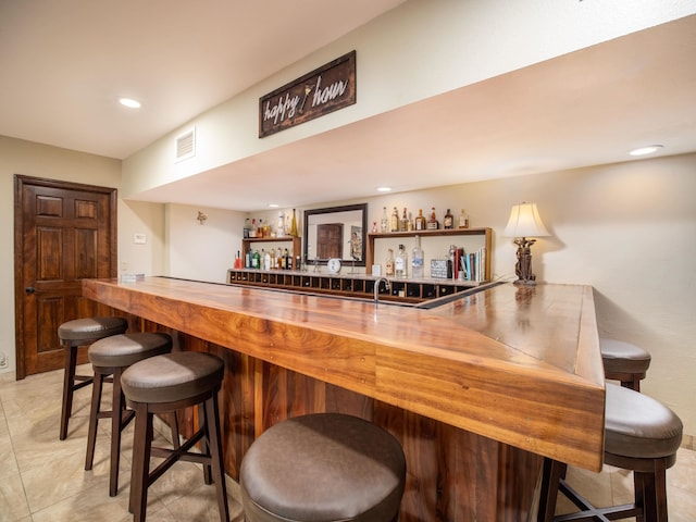 bar featuring light tile patterned flooring and butcher block counters