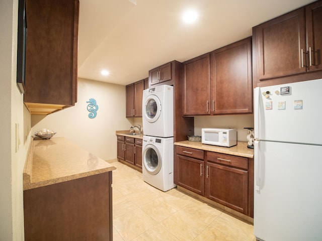 laundry area featuring sink, light tile patterned floors, and stacked washing maching and dryer