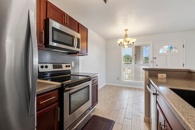 kitchen with a chandelier, appliances with stainless steel finishes, light hardwood / wood-style flooring, and hanging light fixtures