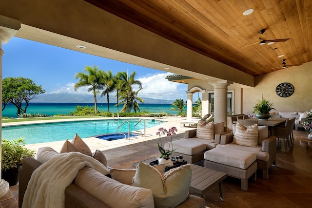 view of swimming pool featuring ceiling fan, a water view, an outdoor living space, and a patio