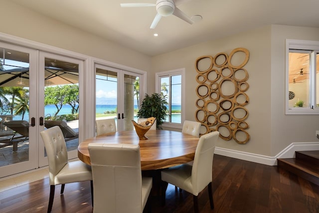 dining space featuring a water view, dark hardwood / wood-style flooring, ceiling fan, and french doors