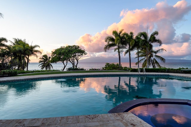 pool at dusk featuring a water view