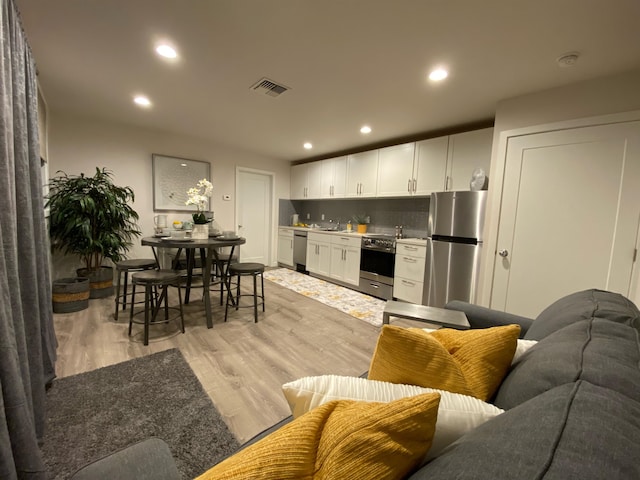 living room with light hardwood / wood-style floors and wet bar