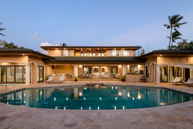 back house at dusk featuring a patio