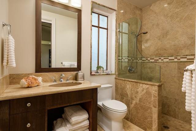 bathroom with tiled shower, vanity, and toilet