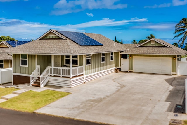 view of front facade featuring a porch, a garage, and solar panels