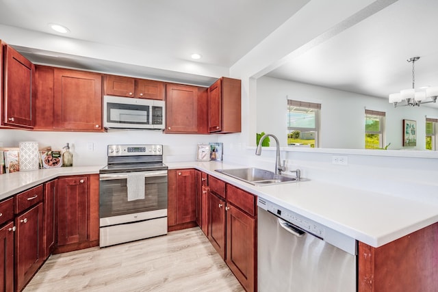 kitchen featuring a chandelier, light hardwood / wood-style floors, appliances with stainless steel finishes, pendant lighting, and sink