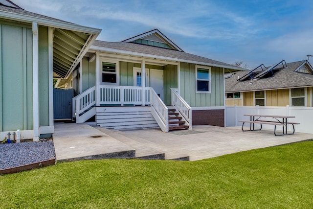 rear view of property featuring covered porch and a lawn