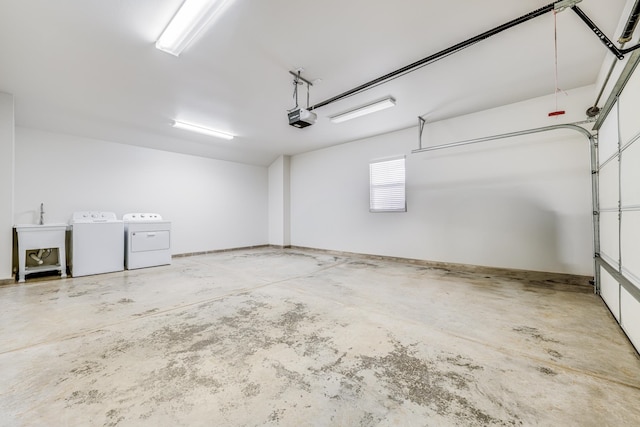 garage with independent washer and dryer, a garage door opener, and sink