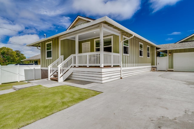 view of front of home featuring a porch, a garage, and a front yard