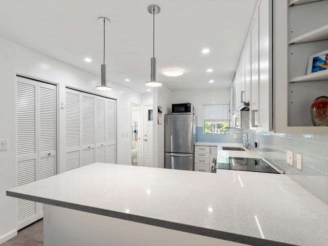68 Walaka St Unit 5, Kihei, HI 96753 - kitchen with stainless steel appliances, a peninsula, decorative backsplash, light stone countertops, and hanging light fixtures