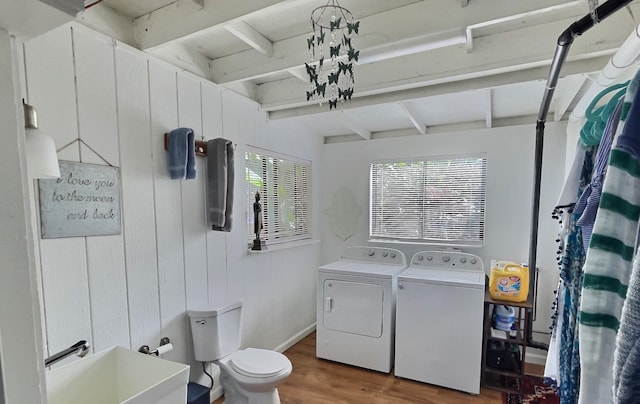 bathroom featuring toilet, a wealth of natural light, separate washer and dryer, and wooden walls