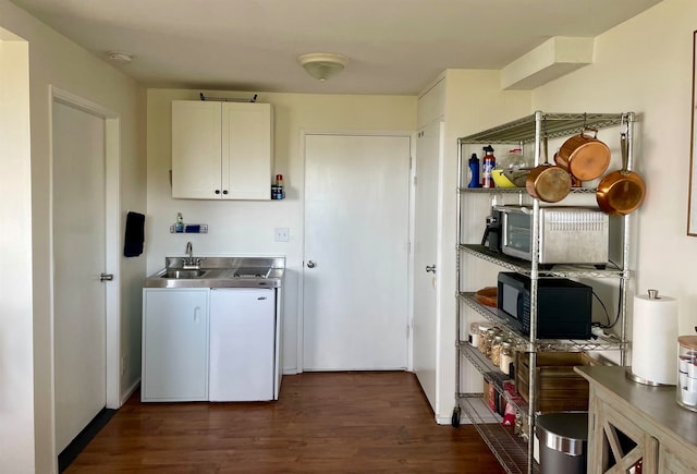 laundry area featuring sink, washer and clothes dryer, dark hardwood / wood-style floors, and cabinets