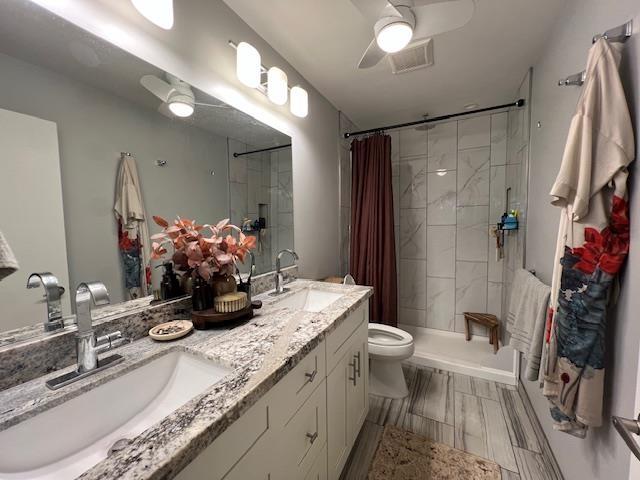 15 Kulanihakoi St Unit 9E, Kihei, HI 96753 - full bathroom featuring tiled shower, toilet, ceiling fan, and double vanity