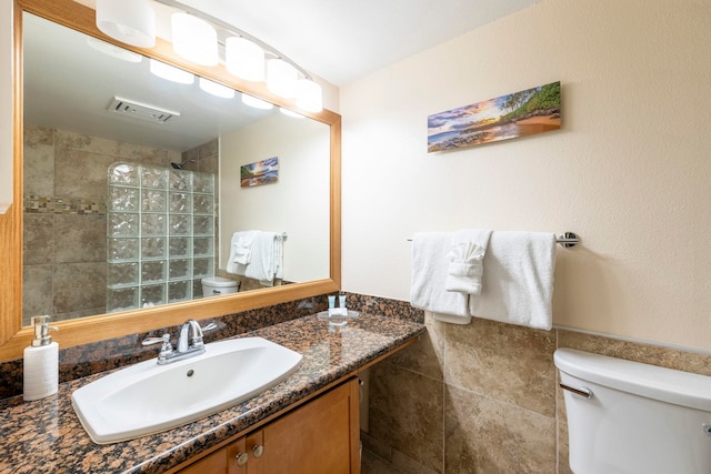 bathroom with vanity, tile walls, and toilet