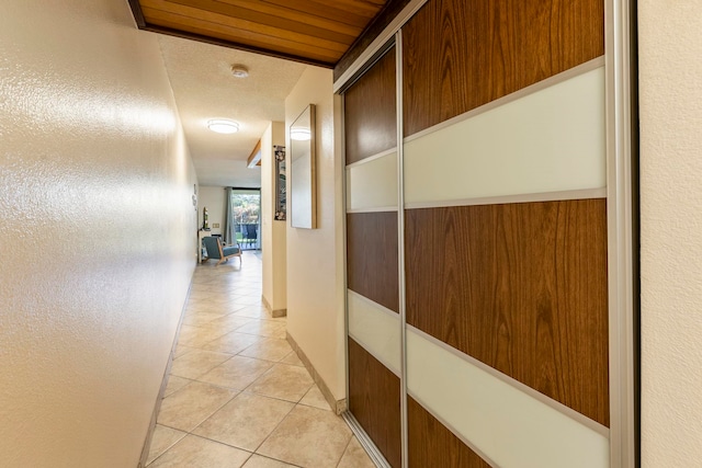 hallway with light tile patterned floors and wood walls