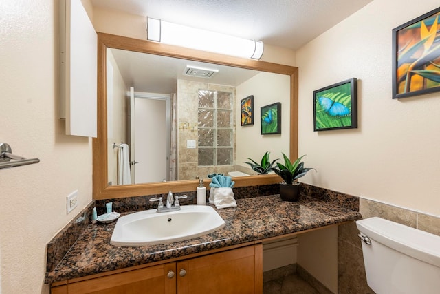 bathroom with an enclosed shower, vanity, toilet, and tile walls