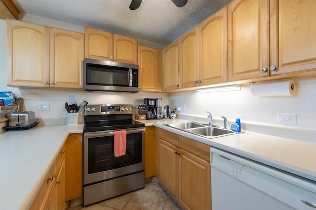 kitchen with sink, light tile patterned floors, a textured ceiling, light brown cabinetry, and stainless steel appliances