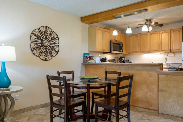 kitchen featuring kitchen peninsula, ceiling fan, light tile patterned floors, light brown cabinets, and beam ceiling