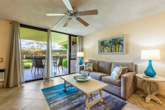 living room featuring ceiling fan, expansive windows, light tile patterned floors, and a textured ceiling