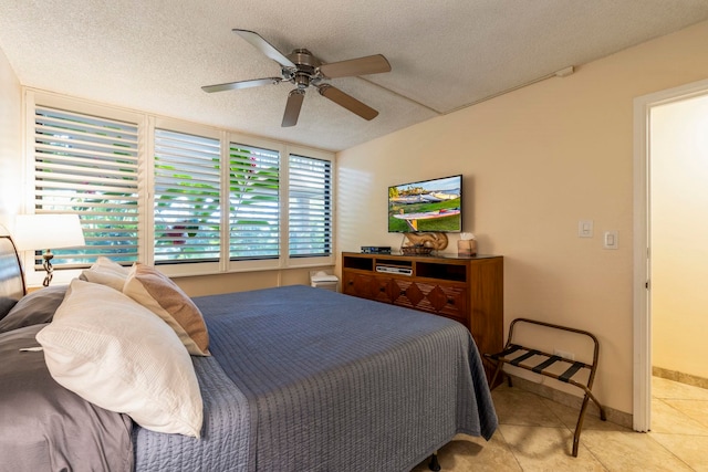 bedroom with ceiling fan, light tile patterned floors, and a textured ceiling